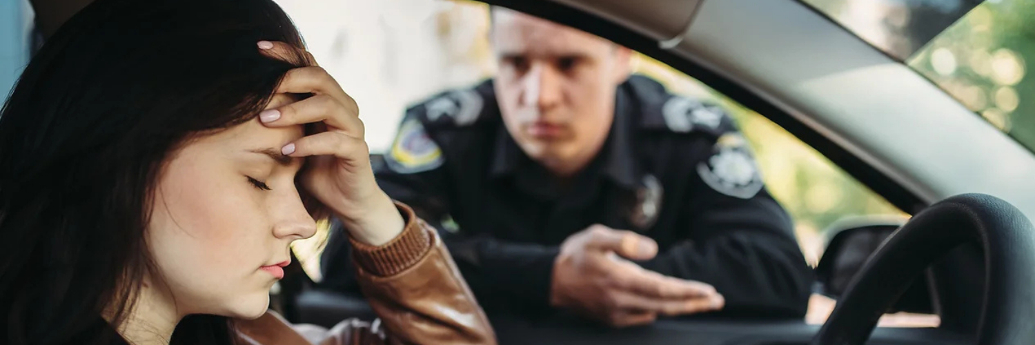 Image of a police officer who has pulled over a California for having too dark of window tint.